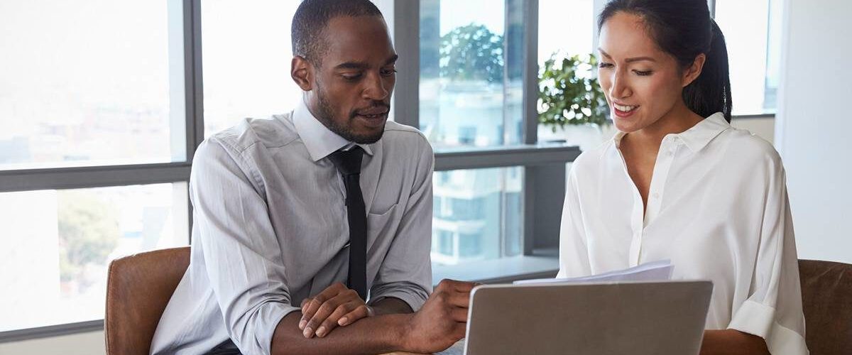 Image of businessman and businesswoman working in office and reviewing benefits of outsourcing payroll