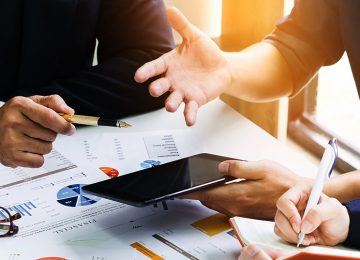 Image of business people discussing EIN with charts and tablet in office