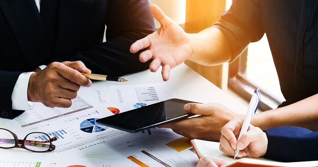 Image of business people discussing EIN with charts and tablet in office