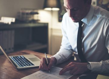 Image of accountant carefully reviewing document with new income tax withholding tables for 2018