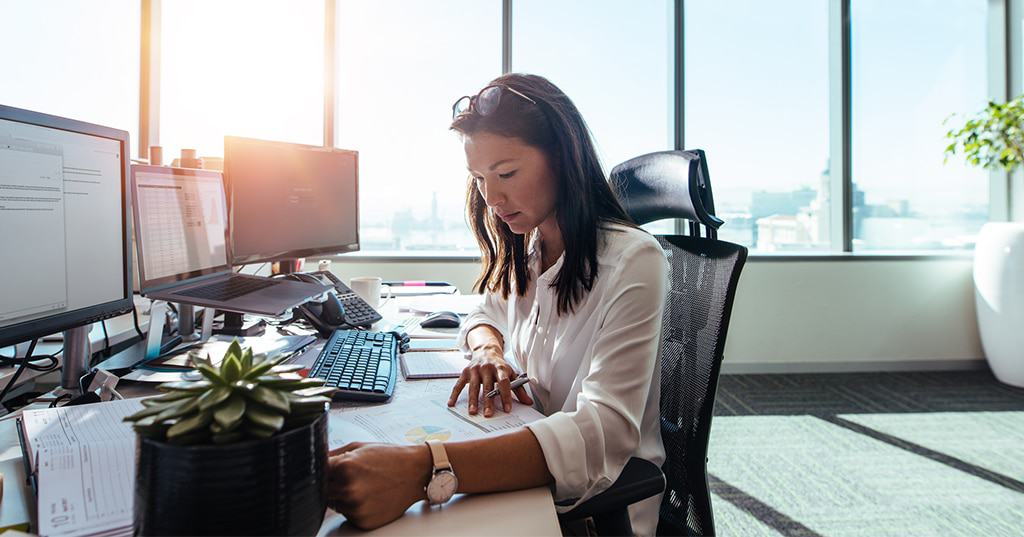 Image of business woman reviewing charts and reports in office