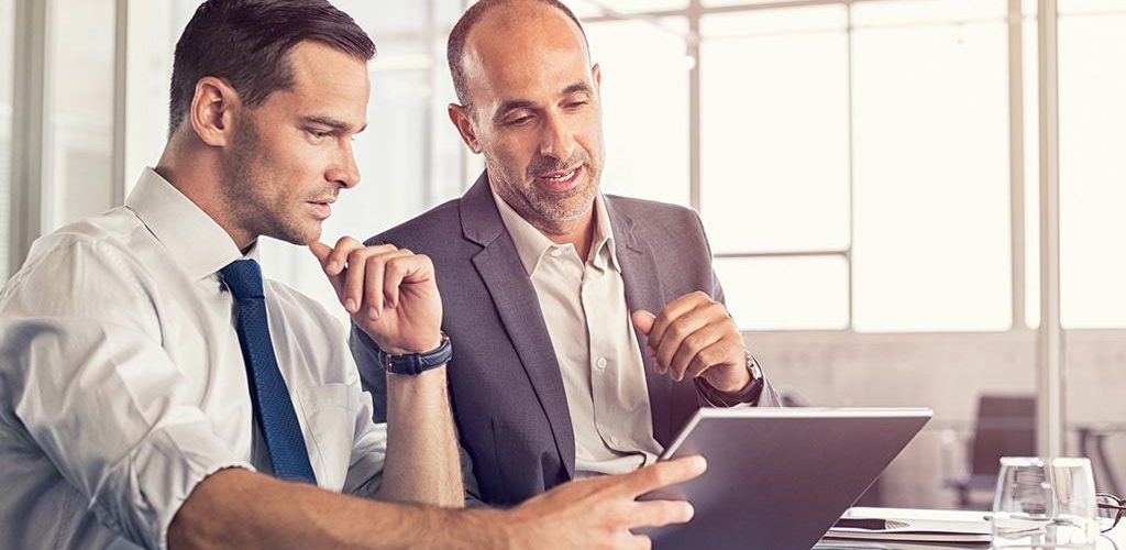 Image of two men in office looking at tablet and discussing business tax reform