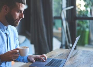 Image of man drinking coffee and using laptop to read about individual tax reform changes