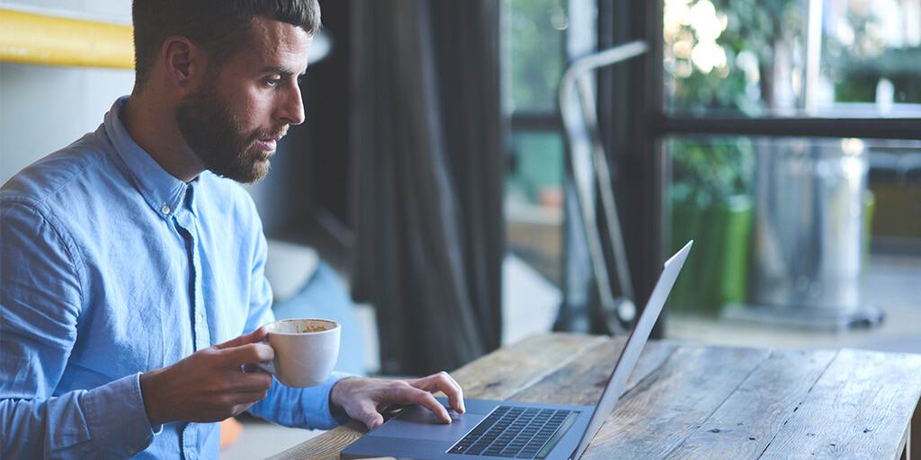 Image of man drinking coffee and using laptop to read about individual tax reform changes