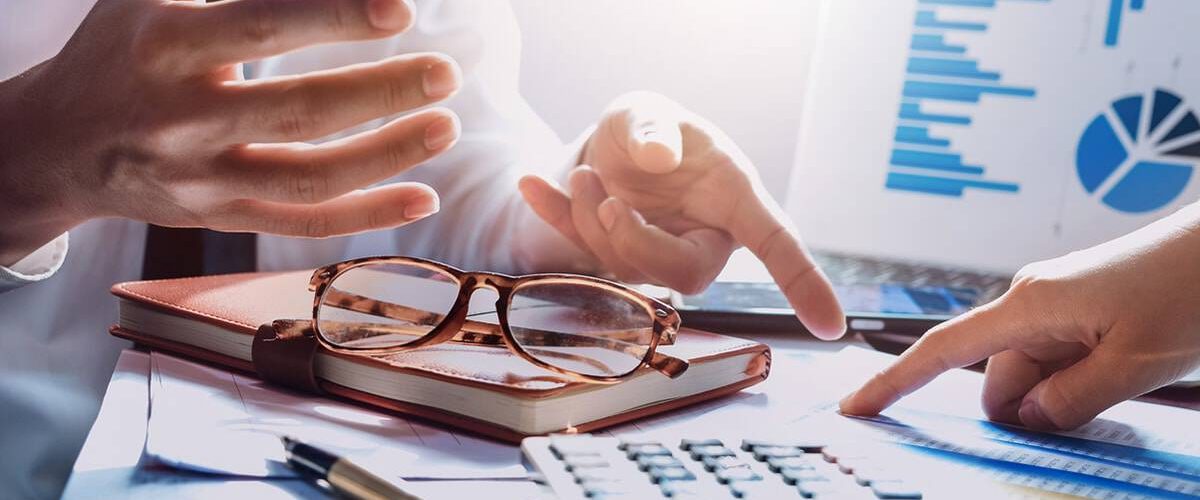 Image of desk with notebook, business charts, and calculator - business colleagues are pointing to changes in Tax Cuts and Jobs Act