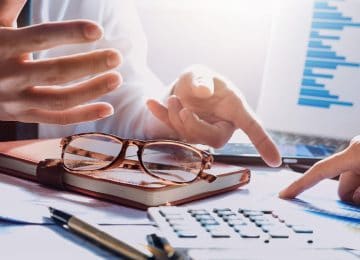 Image of desk with notebook, business charts, and calculator - business colleagues are pointing to changes in Tax Cuts and Jobs Act