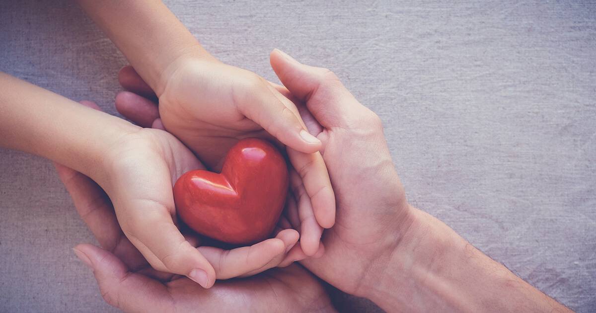 Image of two hands holding a red heart to represent charitable giving