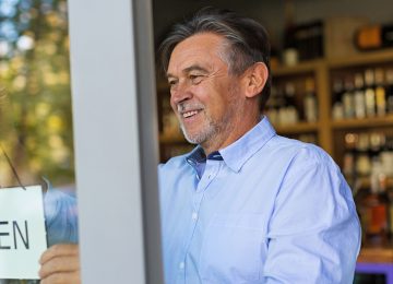 Image of small business owner hanging up open sign in shop