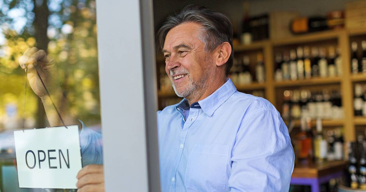 Image of small business owner hanging up open sign in shop