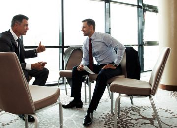 Image of two men in conference room discussing tax saving and how to apply deductions, exclusions, and credits