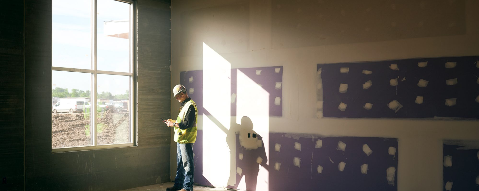 Image of construction worker checking phone at construction site