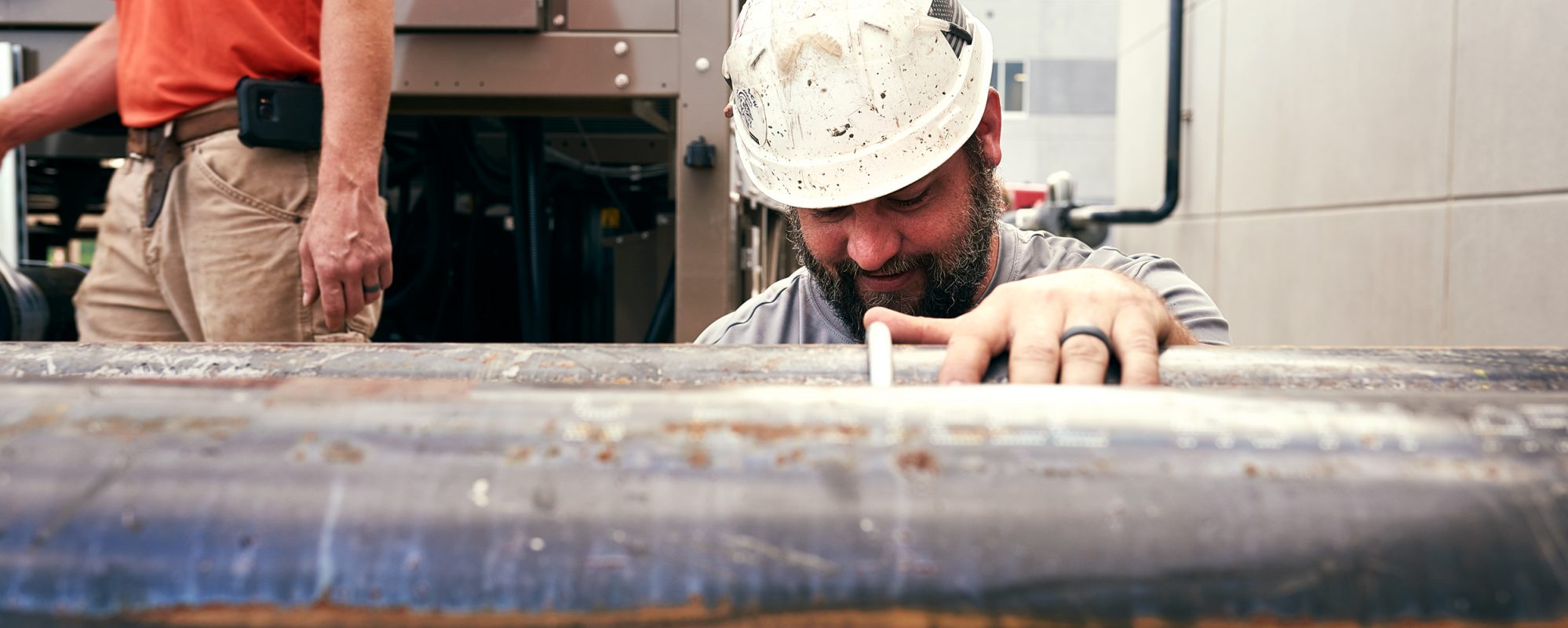 Construction worker looking at on pipe - payroll services