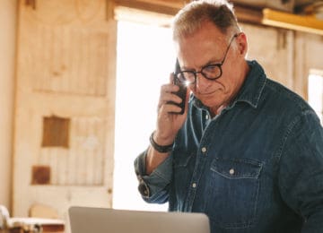 Senior male carpenter standing in workshop is targeted in social security number phone scam