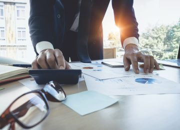 Close up image of businessman using calculator to evaluate business costs