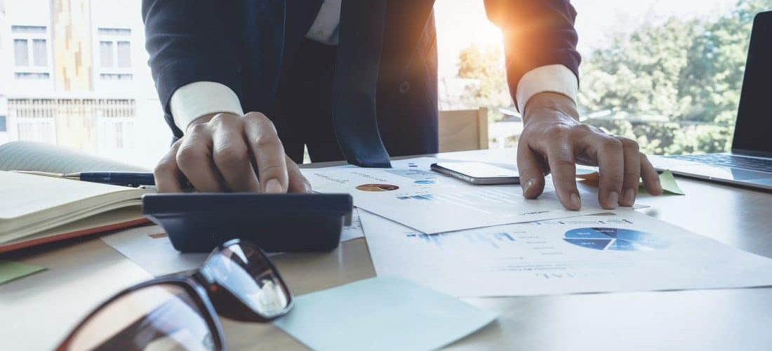 Close up image of businessman using calculator to evaluate business costs