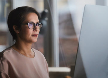 mature woman sits at computer and reads the new net operating loss rules under the cares act