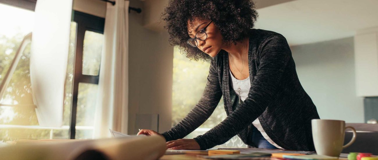 Young female standing at desk and reviewing 2021 tax rates and numbers