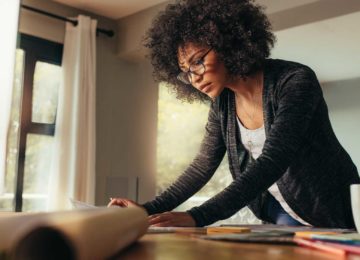 Young female standing at desk and reviewing 2021 tax rates and numbers