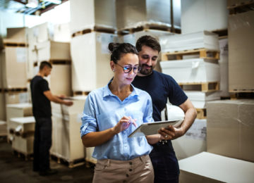 Finance personnel in a warehouse discussing how to account for their PPP loan