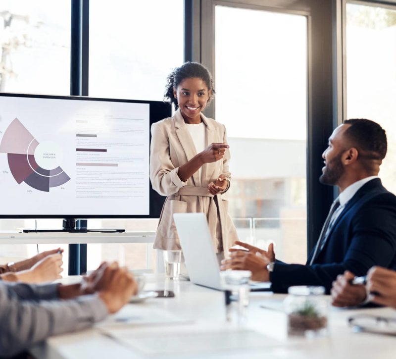 Young businesswoman delivering a presentation to her colleagues in the boardroom of a modern office