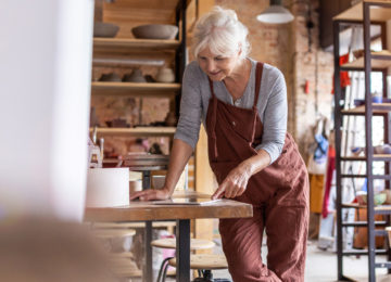 mature woman reviews retirement plan provisions in the cares act in her pottery studio