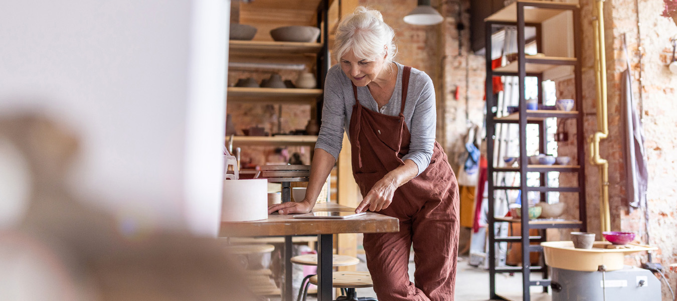 mature woman reviews retirement plan provisions in the cares act in her pottery studio