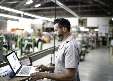 A manufacturer using laptop while working in a factory and researching tax mistakes to avoid