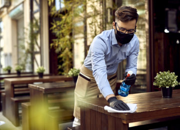 Young waiter cleaning tables after passing of American Rescue Plan Act of 2021