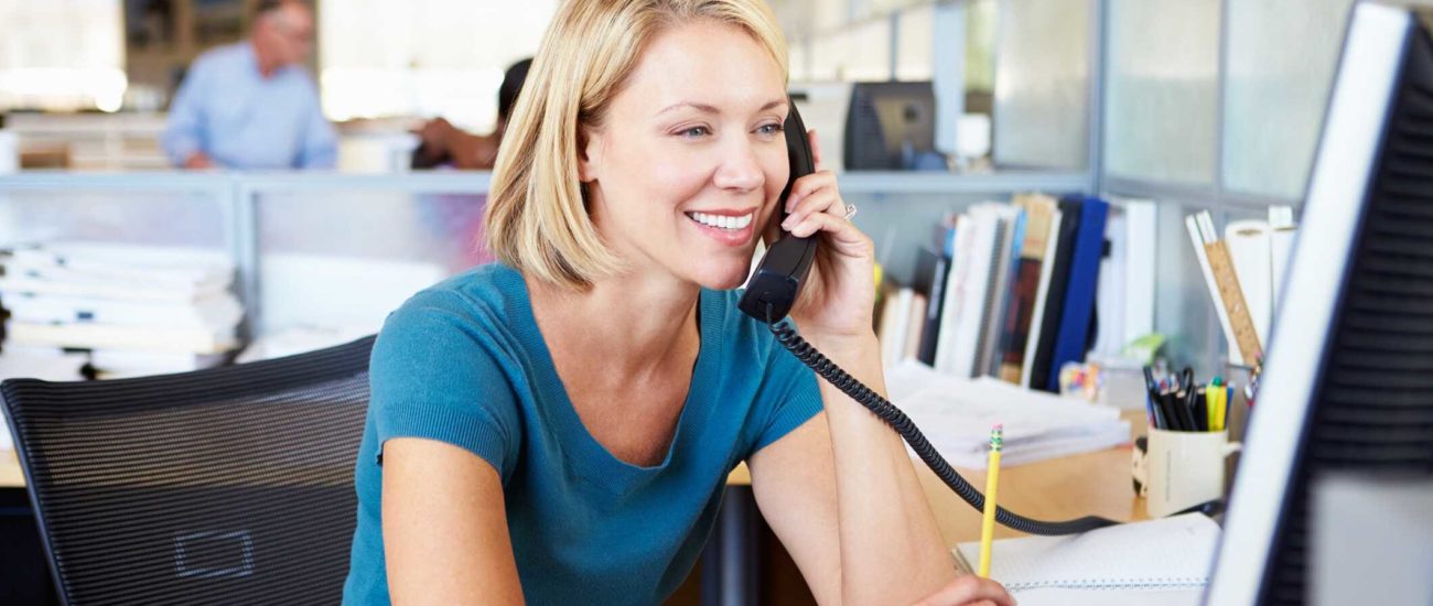 Image of woman talking on phone in office and paying state and local tax