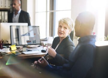 Image of business colleagues working in office and discussing business reports and plans