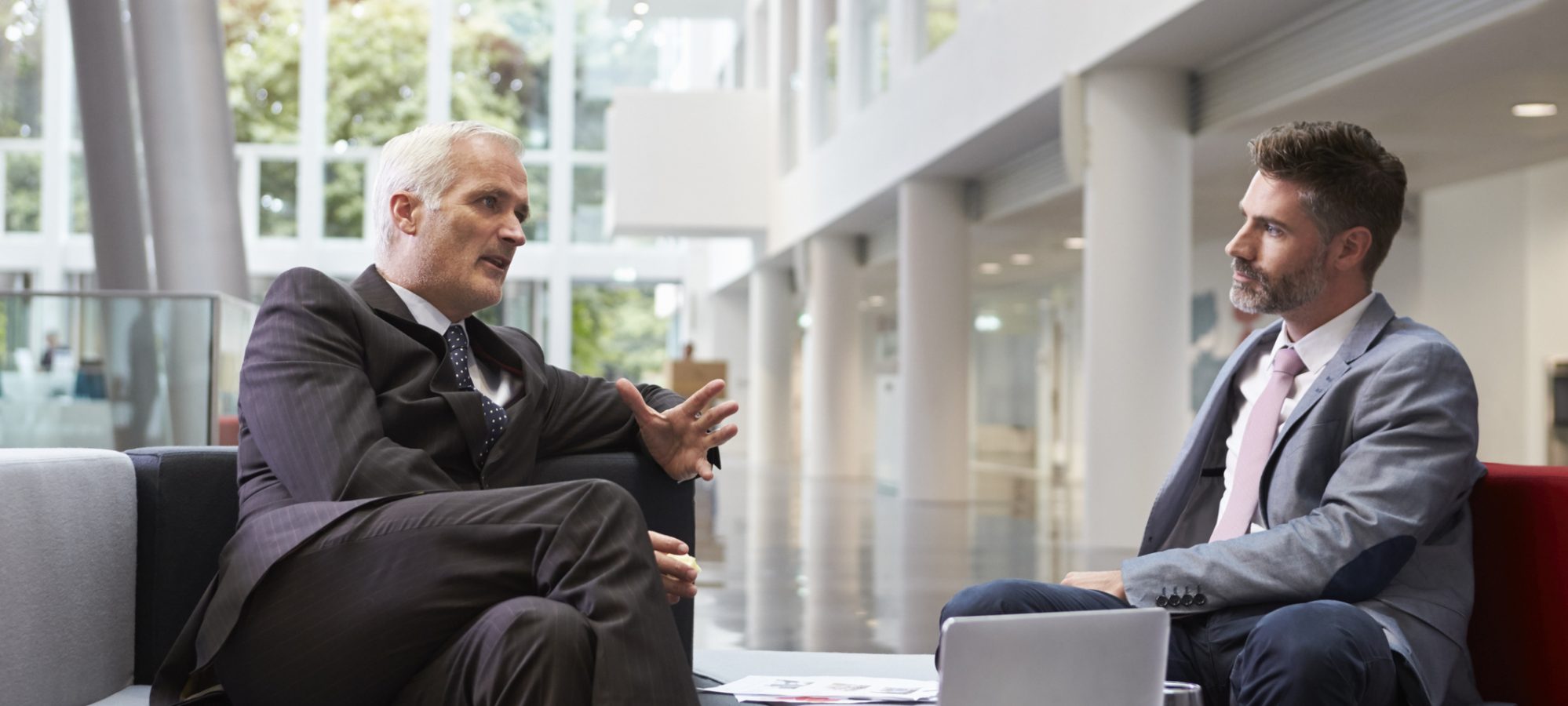 Image of two businessmen meeting in lobby area of office discussing business valuation