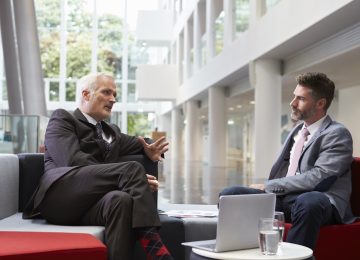 Image of two businessmen meeting in lobby area of office discussing business valuation