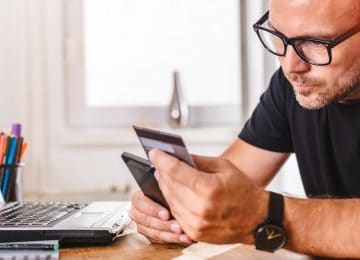 Image of man paying for online purchase with credit card on smart phone