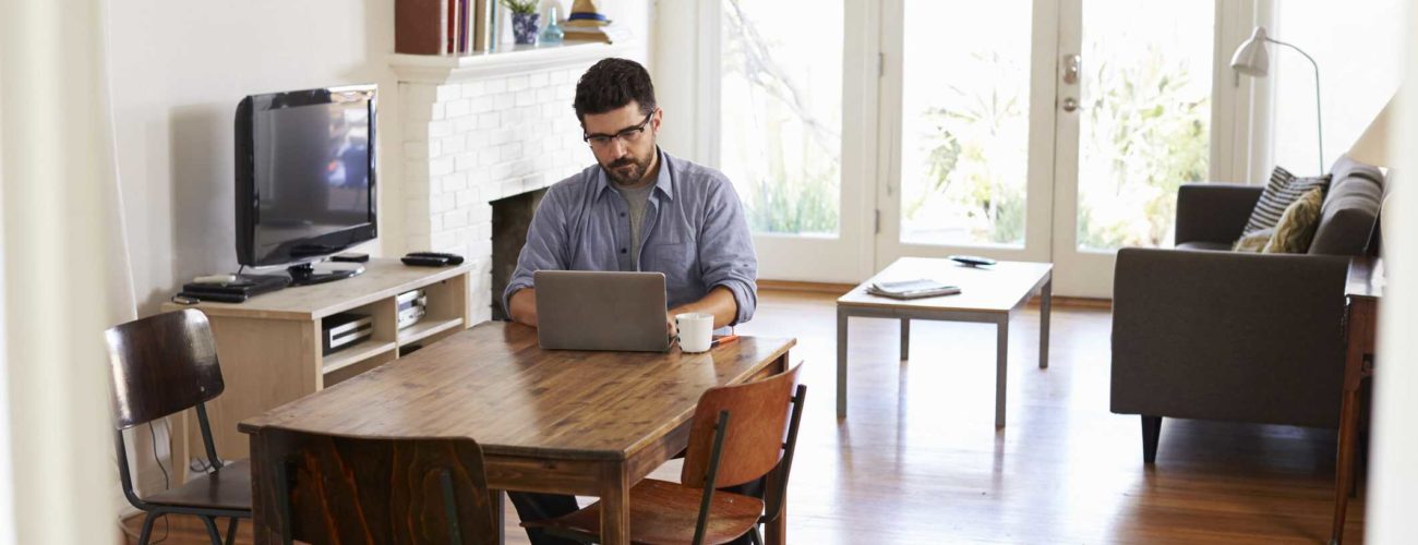 Image of man at home using laptop to access SafeSend Returns on dining table