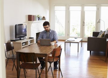 Image of man at home using laptop to access SafeSend Returns on dining table