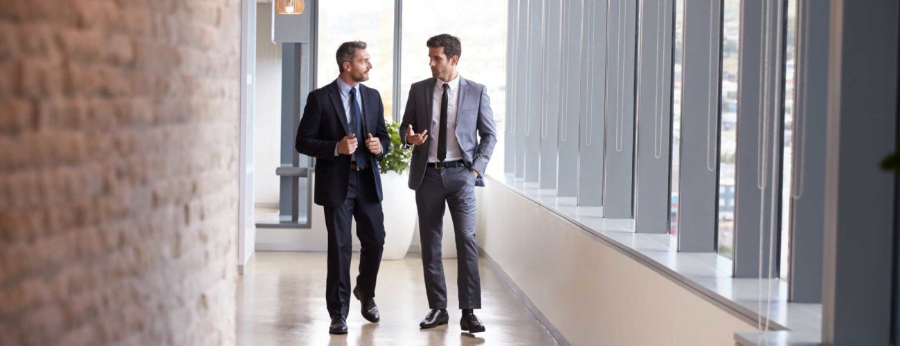 Image of two businessmen having informal meeting about qualified business income deduction in office corridor