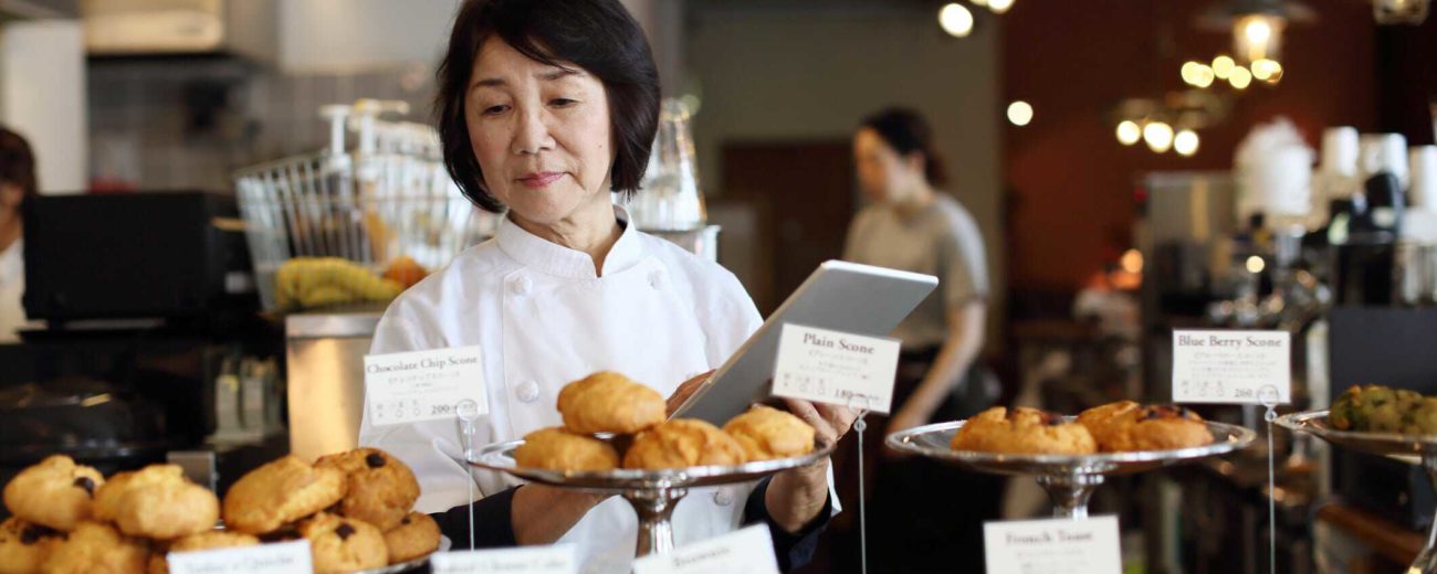 Image of business owner working in bakery shop, consider selling your business