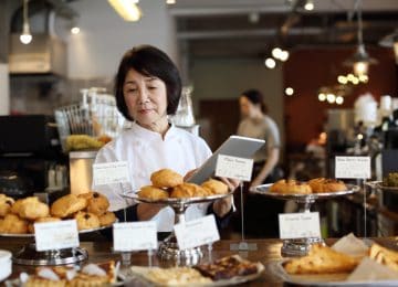 Image of business owner working in bakery shop, consider selling your business