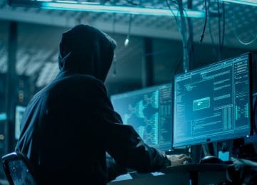 Image of hooded hacker breaking into data servers to enact a tax scam