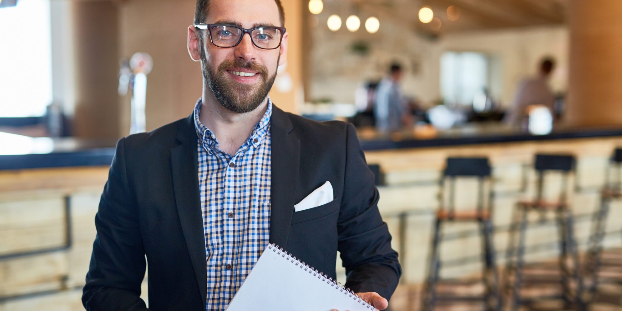 Image of businessman with notepad looking at camera in a restaurant