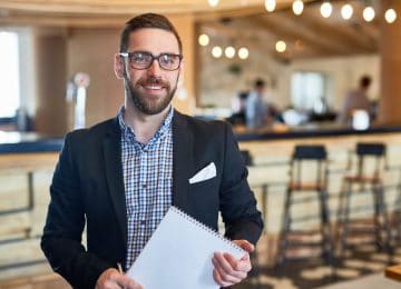 Image of businessman with notepad looking at camera in a restaurant