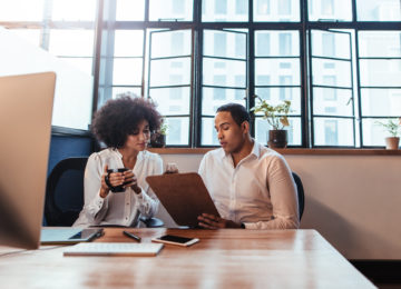 Two professionals discussing an employee benefit plan audit while sitting at a desk