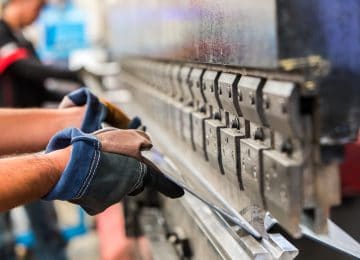 Image of man bending sheet metal in factory - tangible personal property or real property