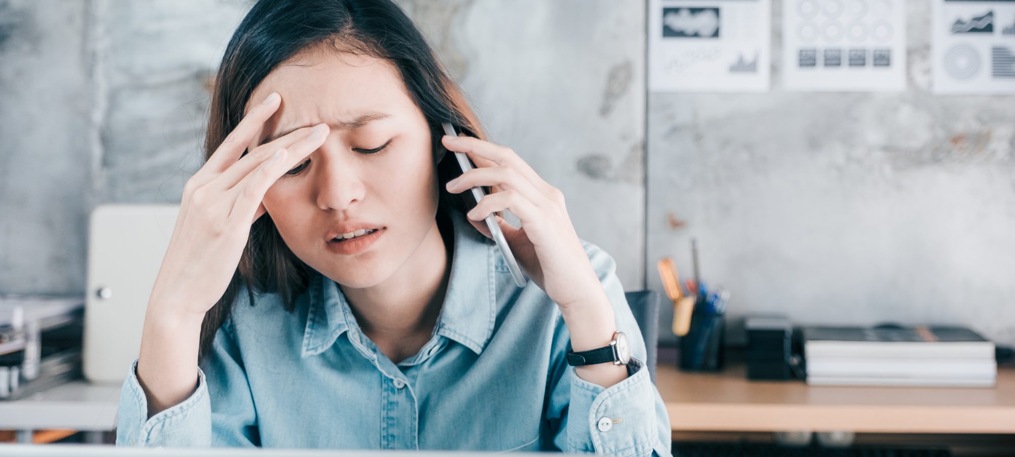 Image of young business woman who's on phone with current payroll provider and stressed