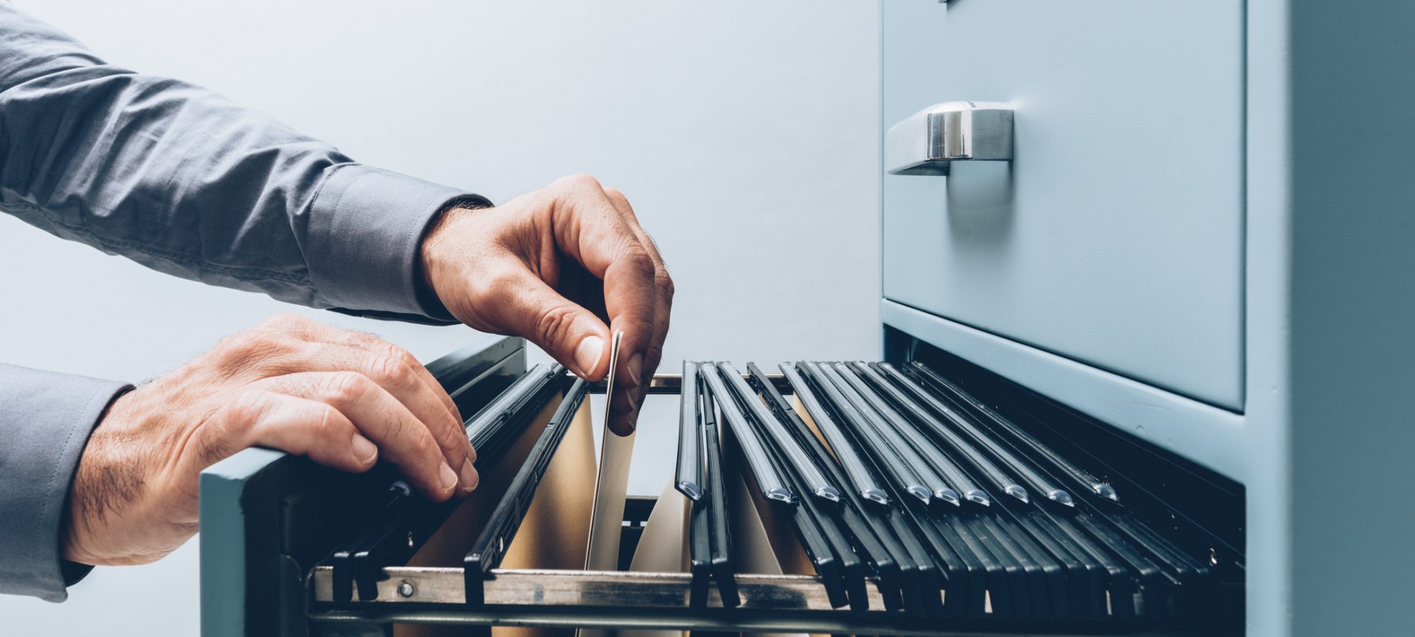 Image of person filing documents in filing cabinet - record retention