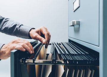 Image of person filing documents in filing cabinet - record retention