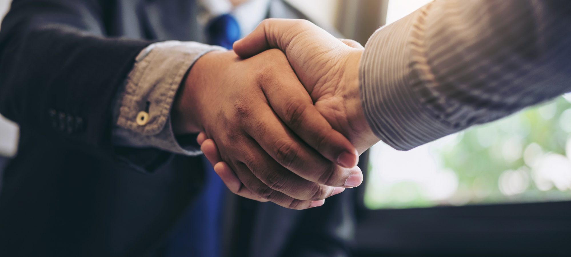 Image of two business men shaking hands during meeting - Sage Group and Intacct Corporation combine