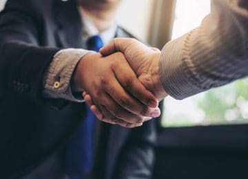 Image of two business men shaking hands during meeting - Sage Group and Intacct Corporation combine