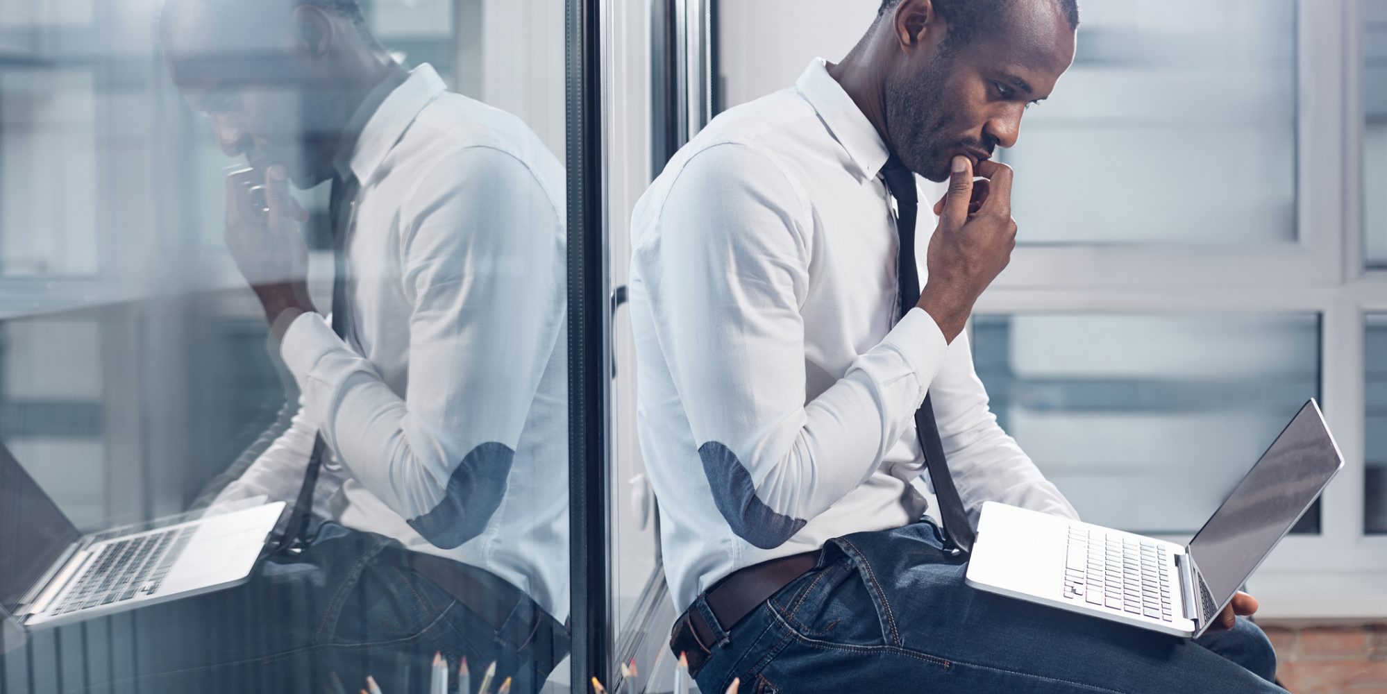 Image of business man sitting on desk and carefully reviewing a phishing attempt on his laptop