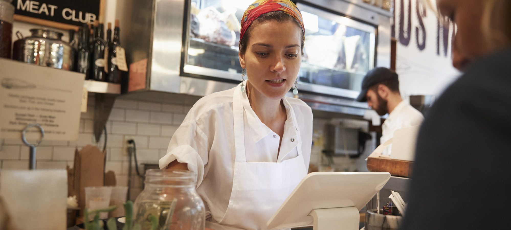 Young woman serving a customer at small shop - minimum wage